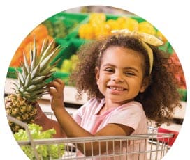 A girl holding a pineapple at the grocery store