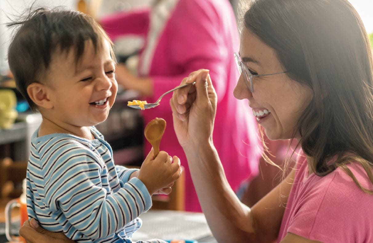 Woman feeding a little boy a spoonful of cereal