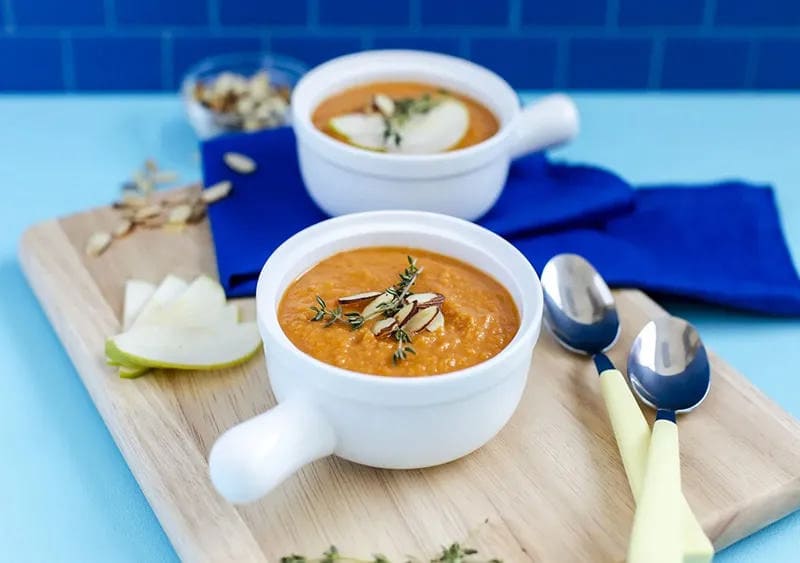 Creamy Butternut Squash and Apple Soup in a bowl with a lemon slice on the side.