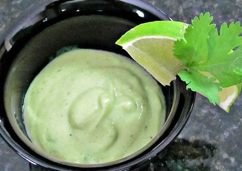 Creamy Vegan Avocado Salad Dressing in a bowl with a slice of lime